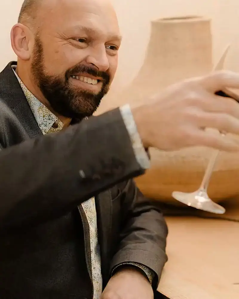 Henk proost lachend met een glas in de hand